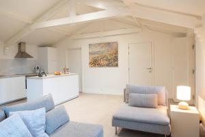 a living room with a couch and chairs and a kitchen at Heart at Sea - De Haan in De Haan