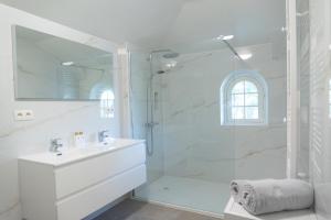 a white bathroom with a shower and a sink at Heart at Sea - De Haan in De Haan