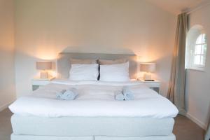 a bedroom with a large white bed with two lamps at Heart at Sea - De Haan in De Haan