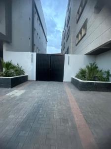 um parque de estacionamento com um portão preto entre dois edifícios em Jamal Royal Apartments em Medina