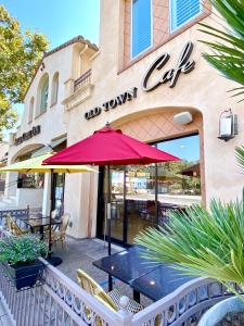 una cafetería con una sombrilla roja frente a un edificio en Bella Capri Inn and Suites en Camarillo