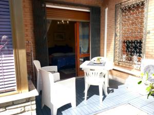 eine Terrasse mit weißen Stühlen und einem weißen Tisch in der Unterkunft Sky Room in Sanremo