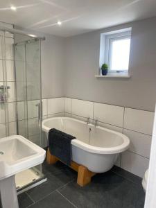 a bathroom with a tub and a shower and a sink at Tregue Cottage in Camelford