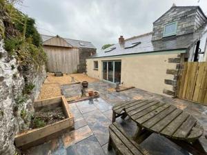 a patio with a wooden bench and a house at Tregue Cottage in Camelford