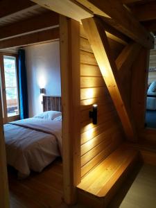 un lit dans une chambre avec un mur en bois dans l'établissement Le grenier du Roux, à Abriès