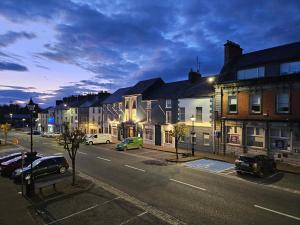 a city street at night with cars parked on the street at Main Street Swinford! in Swinford