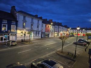 a city street at night with cars parked on the street at Main Street Swinford! in Swinford
