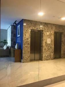a lobby with two elevators and a stone wall at Magnifico apto com vista para o mar!!!! in Guarapari