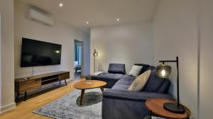 Una sala de estar con un sofá azul y un televisor. en Le Duplex VIP, en Montreal