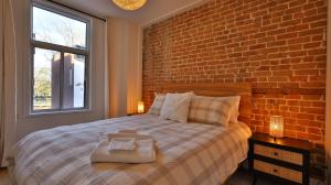 Un dormitorio con una cama grande con una pared de ladrillo. en Le Duplex VIP, en Montreal