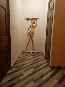 Un dipinto di una donna che tiene un ombrello in un corridoio di Palm Grove lodge a Busua
