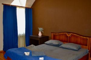 a bedroom with a bed with blue sheets and a window at Отель Ренессанс in Dnipro
