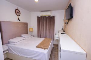 um pequeno quarto com uma cama e uma televisão em Casa aconchegante em Goiânia em Goiânia