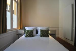 uma cama branca com duas almofadas e uma janela em Upstairs em Antuérpia