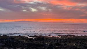 um pôr-do-sol sobre o oceano com uma praia rochosa em New Luxury Apartment First Line Sea View em Palm-mar