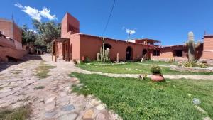 a building with a grass yard next to a house at Cabañas Tierra Andina in Tilcara