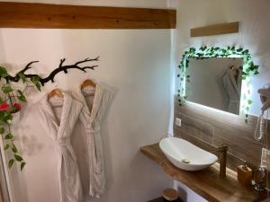 une salle de bain avec trois robes accrochées au mur dans l'établissement Cottage River & Spa, à Saint-Ilpize 41 autres photos