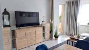 a living room with a flat screen tv on a wooden dresser at Piastowska Lake in Ostróda
