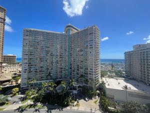 a tall building with palm trees in front of a city at Ilikai Apt 2127 - Spacious Studio with Spectacular Ocean & Harbor Views in Honolulu