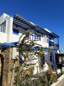 a white house with blue windows and plants at Anna'sHouse in Agios Ioannis