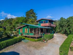 una casa con una fachada verde y árboles en Campo Verde B&B - Monteverde Costa Rica en Monteverde Costa Rica