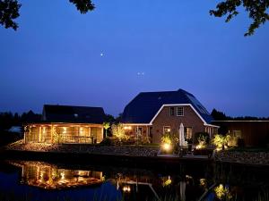 una casa iluminada por la noche con luces en B&B de Wiekeborg en Oude Pekela