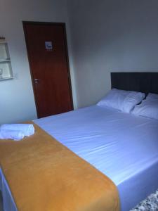 a bedroom with two beds and a wooden door at Quarto privativo 01 in Sinop
