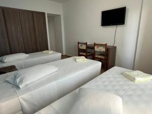 Habitación de hotel con 2 camas y TV de pantalla plana. en Hotel Quatro Estações, en Guarapari