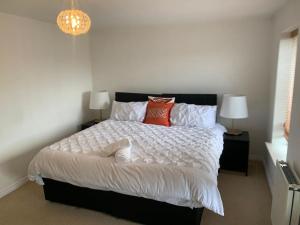 1 dormitorio con 1 cama grande con sábanas blancas y almohadas rojas en Cozy Luxurious And Spacious 4 Bed Home, en West Thurrock