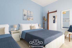 een slaapkamer met 2 bedden en blauwe muren bij Scent of the Sea Apartment - L'Opera Group in La Spezia