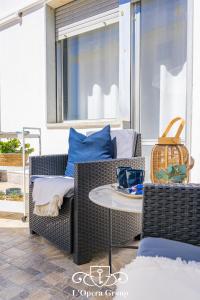 Un patio con una silla de mimbre y una mesa. en Scent of the Sea Apartment - L'Opera Group, en La Spezia