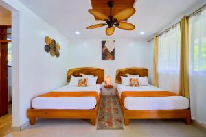 two beds in a room with a ceiling fan at Olinca Boutique Hotel in Puerto Viejo