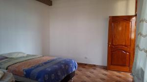 1 dormitorio con 1 cama y puerta de madera en Disfruta la Selva Peruana Pto.M, en Puerto Maldonado