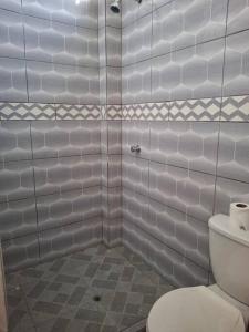 La salle de bains blanche est pourvue d'une douche et de toilettes. dans l'établissement Disfruta la Selva Peruana Pto.M, à Puerto Maldonado