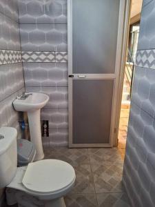 uma casa de banho com um WC, um lavatório e uma porta em Disfruta la Selva Peruana Pto.M em Puerto Maldonado