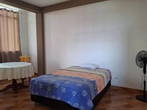 a bedroom with a bed and a table with a fan at Disfruta la Selva Peruana Pto.M in Puerto Maldonado