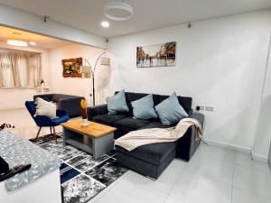 un soggiorno con divano nero e tavolo di Urban Oasis In Harrow 2 Bed Home a Pinner