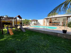 a backyard with a swimming pool and a house at Casa por do Sol amarelo in Araruama