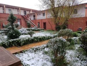 un giardino coperto di neve di fronte a un edificio di Résidence touristique du chêne vert a Ifrane