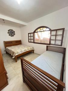 a bedroom with two beds and a window at Casa por do Sol amarelo in Araruama +14 photos