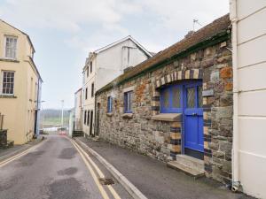 un vieux bâtiment en pierre avec une porte bleue dans une rue dans l'établissement Llys-Yr-Onnen, à Carmarthen