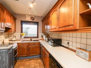 una cocina con armarios de madera y encimeras blancas en Llys-Yr-Onnen en Carmarthen