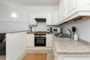 a white kitchen with white cabinets and a sink at Casa El Drago 1 in Breña Baja +13 photos