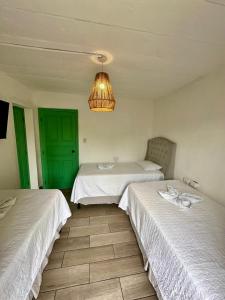 two beds in a room with a green door at Selah hotel & coffee in Antigua Guatemala