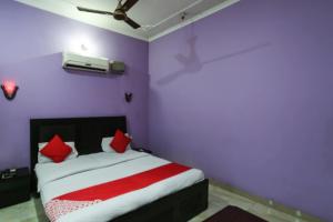 1 dormitorio con paredes moradas y 1 cama con almohadas rojas en OYO Hotel Alfa, en Amb