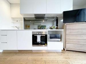 Apartment on Regent في ملبورن: مطبخ فيه دواليب بيضاء وفرن