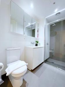 a white bathroom with a toilet and a shower at Apartment on Regent in Melbourne