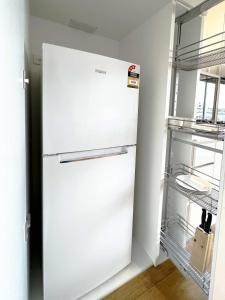 a white refrigerator in a kitchen next to a shelf at Apartment on Regent in Melbourne
