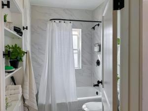 Baño blanco con cortina de ducha y bañera en Step into School Spirit at the Golden Dome Getaway en South Bend