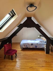 a attic bedroom with a bed and a red chair at Chambre au calme in Le Perray-en-Yvelines